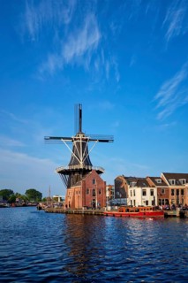 Harlem cityscape, landmark windmill De Adriaan on Spaarne river with boats. Harlem, Netherlands