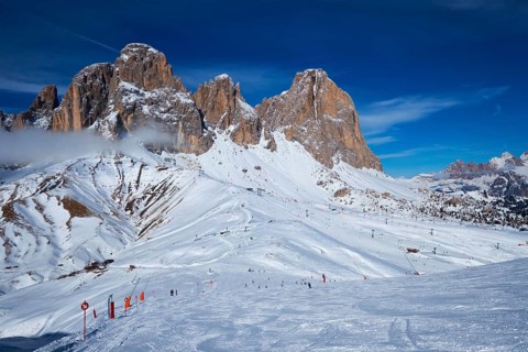 View of a ski resort piste with people skiing in Dolomites in Italy