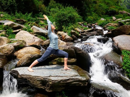 Yoga outdoors, sporty fit woman doing Ashtanga Vinyasa Yoga asana Virabhadrasana 1 Warrior pose