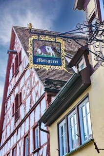 Historical sign of guild butcher craft butchery, in the background historical half-timbered house,