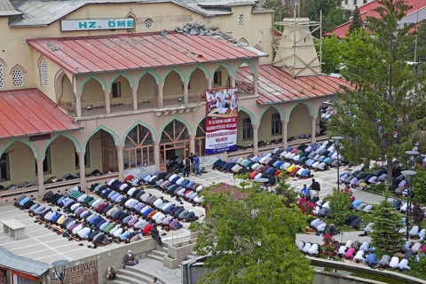 Turkish and Kurdish Muslim men in prostration praying outdoors in front of Islamic mosque for the