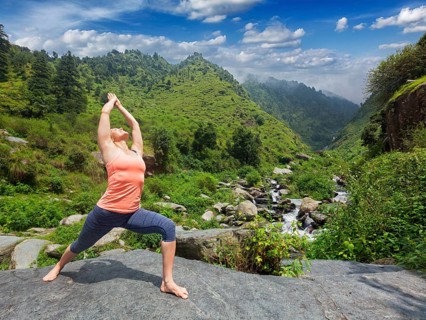 Yoga outdoors, sporty fit woman doing Ashtanga Vinyasa Yoga asana Virabhadrasana 1 Warrior pose