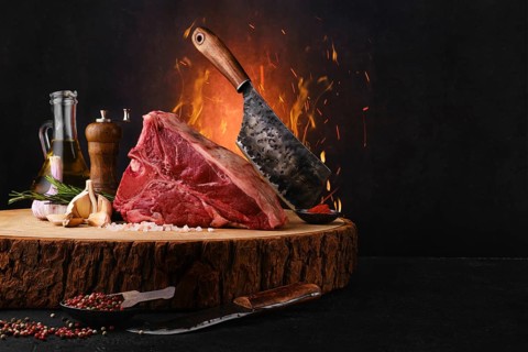 Raw porterhouse steak with ingredients for cooking on wooden log