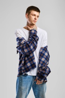 Young cocky man in checkered shirt and jeans touching his throat
