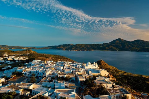 View of Plaka village on Milos island with traditional greek white houses on sunset. Plaka town,