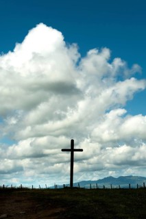 Wooden cross under a cloudy sky. Cezallier plateau. Puy de Dome departement. Auvergne-Rhone-Alpes.