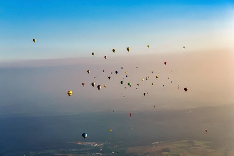 Many different hot air balloons on the way in the blue sky, distance, hot air balloon festival,