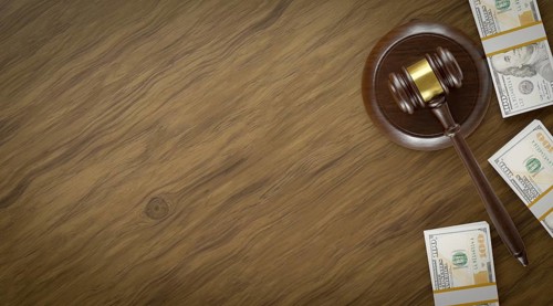 Overhead of gavel resting on a table and stacks of thousands of dollars with room for text
