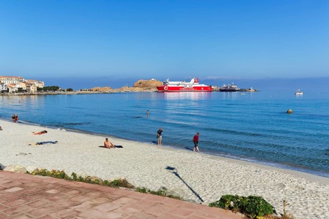 Tourists on the sandy beach, view of ferry in the harbour, L'Île-Rousse, Ile Rousse, Corsica,