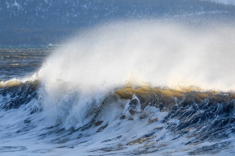 Large wave breaks during winter storm on Kachemak Bay beach, near Home on the Kenai Peninsula,