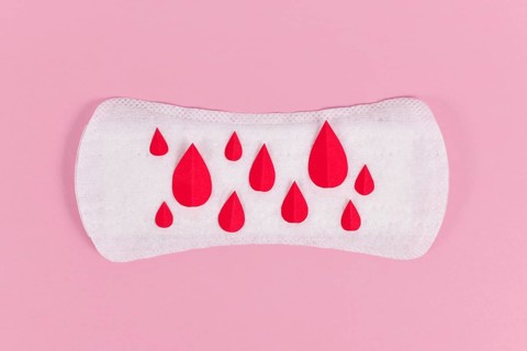 Female period concept with panty liner with symbolic paper blood drops on pink background