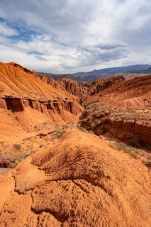 Eroded mountain landscape with sandstone cliffs, canyon with red and orange rock formations,