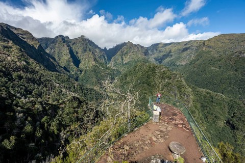 Tourist at a viewpoint, view from the Miradouro dos Balcões, densely overgrown steep mountains,