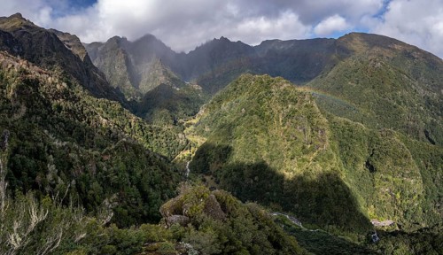 Densely overgrown steep mountains with rainbow, green mountain landscape, view from Miradouro dos