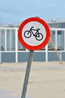 Red bicycle street warning sign on shore of Texel