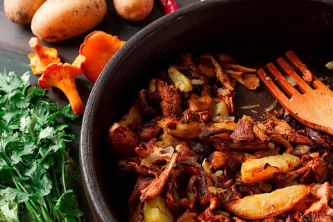 Fried chanterelles with mushrooms, in a clay pan, close-up, top view, selective focus