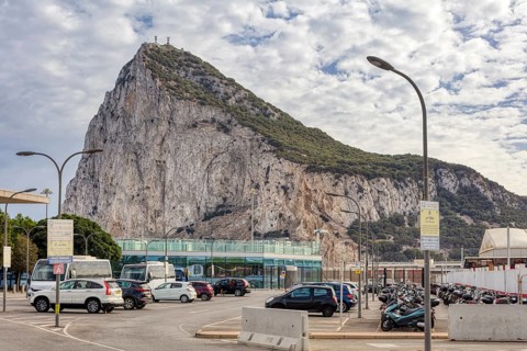 City view with prominent rock and passing cars under a cloudy sky, Gibraltar, Europe