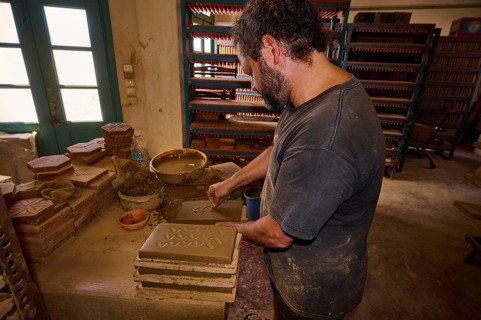 Man moulding clay bricks in a traditional pottery workshop with natural light, Brickworks Patmos