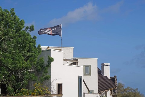 A white house with a waving pirate flag under a blue sky, San Andres, La Palma, Canary Islands,