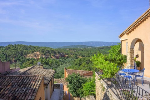 View over the roofs of the village to the ochre cliffs, Roussillon, Département Vaucluse, France,