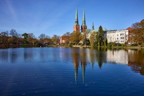 Mill pond with general buildings, Lübeck Cathedral and trees, symmetrical reflections on the water