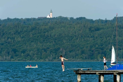 Boy and girl bathing in the lake, children jumping over diving board into the water, jetty of