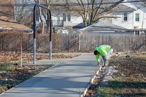 Detroit, Michigan - Workers pour and finish concrete for walking paths in Three Mile Park in