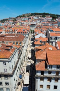 Aerial view of a narrow alley with tall buildings and red tiled roofs in a sunny city, view of