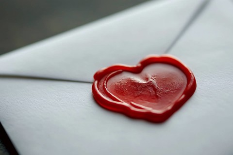 Close up of red heart shaped wax seal on white love letter. Generative AI, AI generated