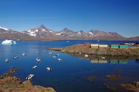 View of small boats in calm fjord, with mountains and colourful houses in the background, Knud