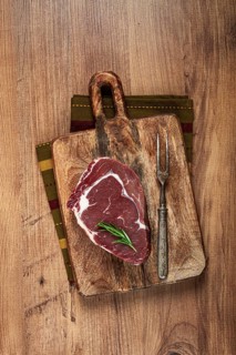 Raw steak, beef steak, rib eye steak, on a cutting board, freshly frozen, with spices and herbs, on