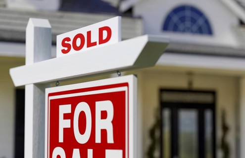 Sold for sale real estate sign in front of new house.