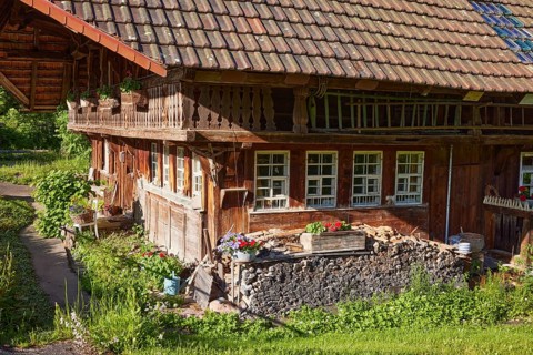 Details of an old Black Forest house with woodpile, windows, balcony and planters in the historic