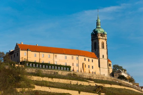 Historic castle with tower on a hill under a blue sky in the evening sun, Melnik Castle, Church of