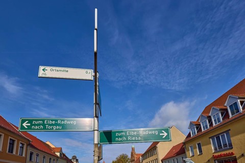 Signpost to the Elbe cycle path to Torgau and Riesa against a blue sky with cirrostratus clouds,