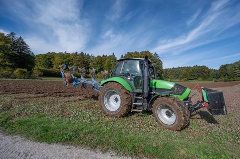 Farmer with tractor ploughing his field with a 5-turn rotary plough, Franconia, Bavaria, Germany,