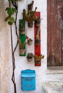 Flower pots with green plants hanging on wooden boards in the colours of Italy, blue post box,