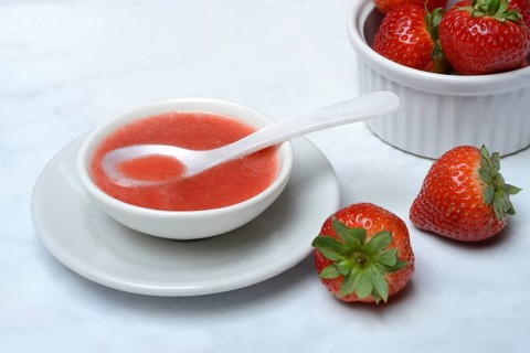Strawberry sauce in small bowls and strawberries, strawberry coulis