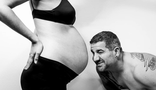 Black and white photo of a man looking at a woman's baby bump