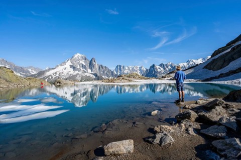 Mountaineer in front of mountain landscape with mountain lake, tourist at Lac Blanc with water