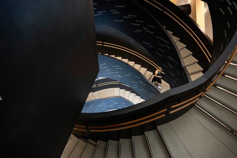 Woman on spiral staircase printed with Finnish words, Oodi Central Library and Cultural Centre,