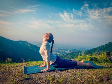 Yoga outdoors, woman practices Ashtanga Vinyasa yoga Surya Namaskar Sun Salutation asana Urdhva