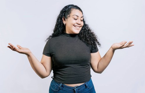 Smiling latin woman comparing with palms hands isolated. Happy girl balancing product with palms