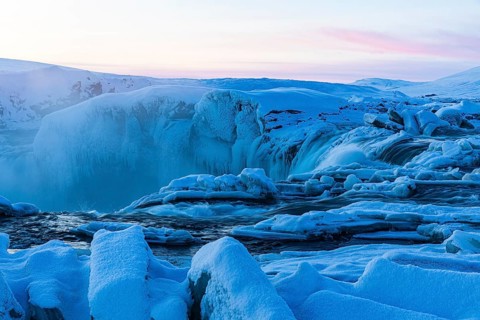 Icefall at the edge of the Godafoss waterfall at dawn, snow-covered landscape, Northern Iceland