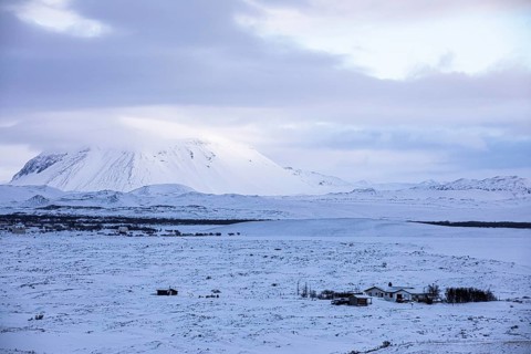Snow-covered extinct volcano Hverfjall, lonely farmhouse in front, near Lake Myvatn, Northern