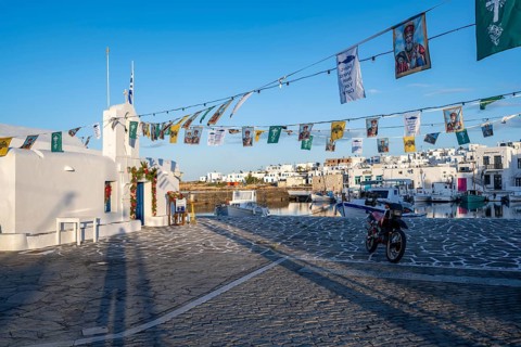 White Cycladic Greek Orthodox Church of Agios Nikolaos, decorated with flags, harbour of Naoussa,
