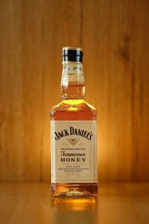 2021, 23 February, Minsk, Belarus, glowing Bottle of Jack Daniel's honey on wooden background (soft