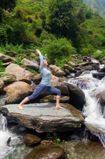 Yoga outdoors, sporty fit woman doing Ashtanga Vinyasa Yoga asana Virabhadrasana 1 Warrior pose
