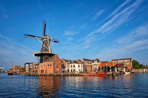Harlem cityscape, landmark windmill De Adriaan on Spaarne river with boats. Harlem, Netherlands