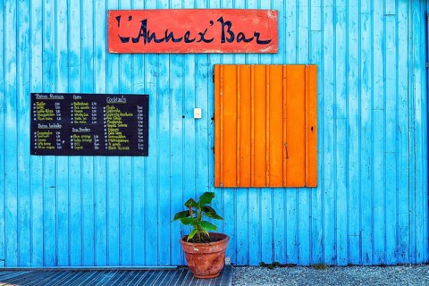 Colourful hut, wooden facade of a bar with orange closed shutter and menu, advertising alcoholic